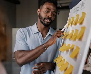 Team member mapping out a marketing plan with sticky notes during a product design session